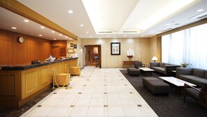 A hotel lobby with a reception desk, seating area, and a clock on the wall. - Hotel Sunroute Asakusa (Tokyo)