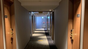 A hotel hallway with carpeted floors, wooden doors, and a ceiling with recessed lighting. - Hotel Sunroute Asakusa (Tokyo)
