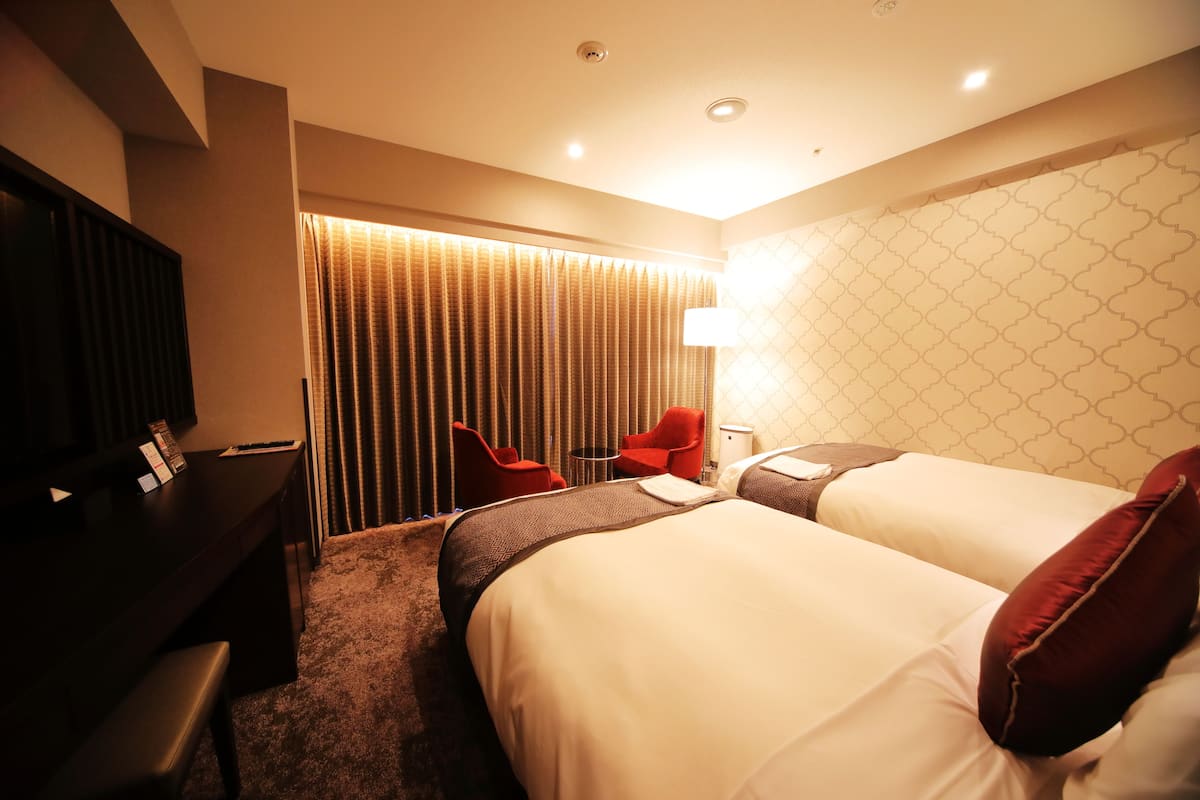A hotel room with a bed, a desk, a chair, and a TV.