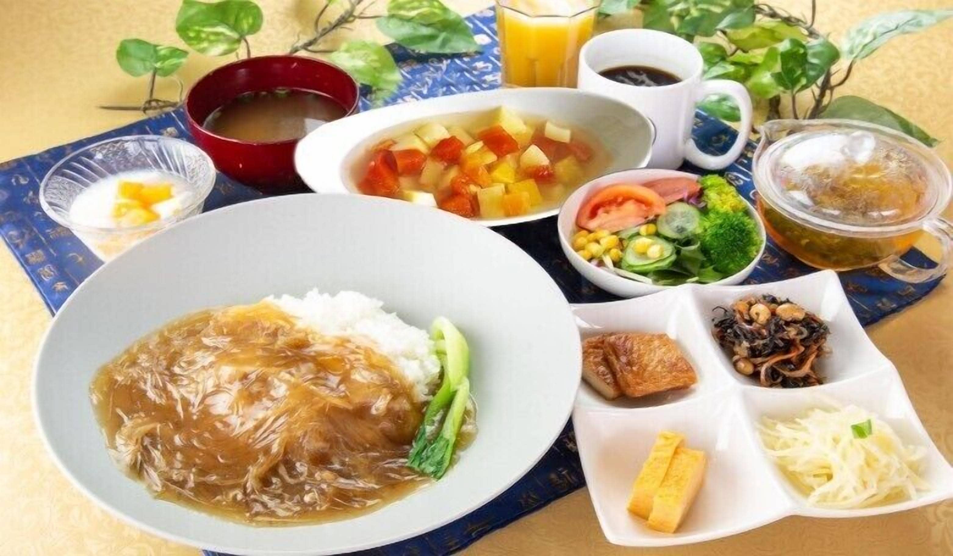 A table with various dishes including rice, vegetables, and a soup bowl.