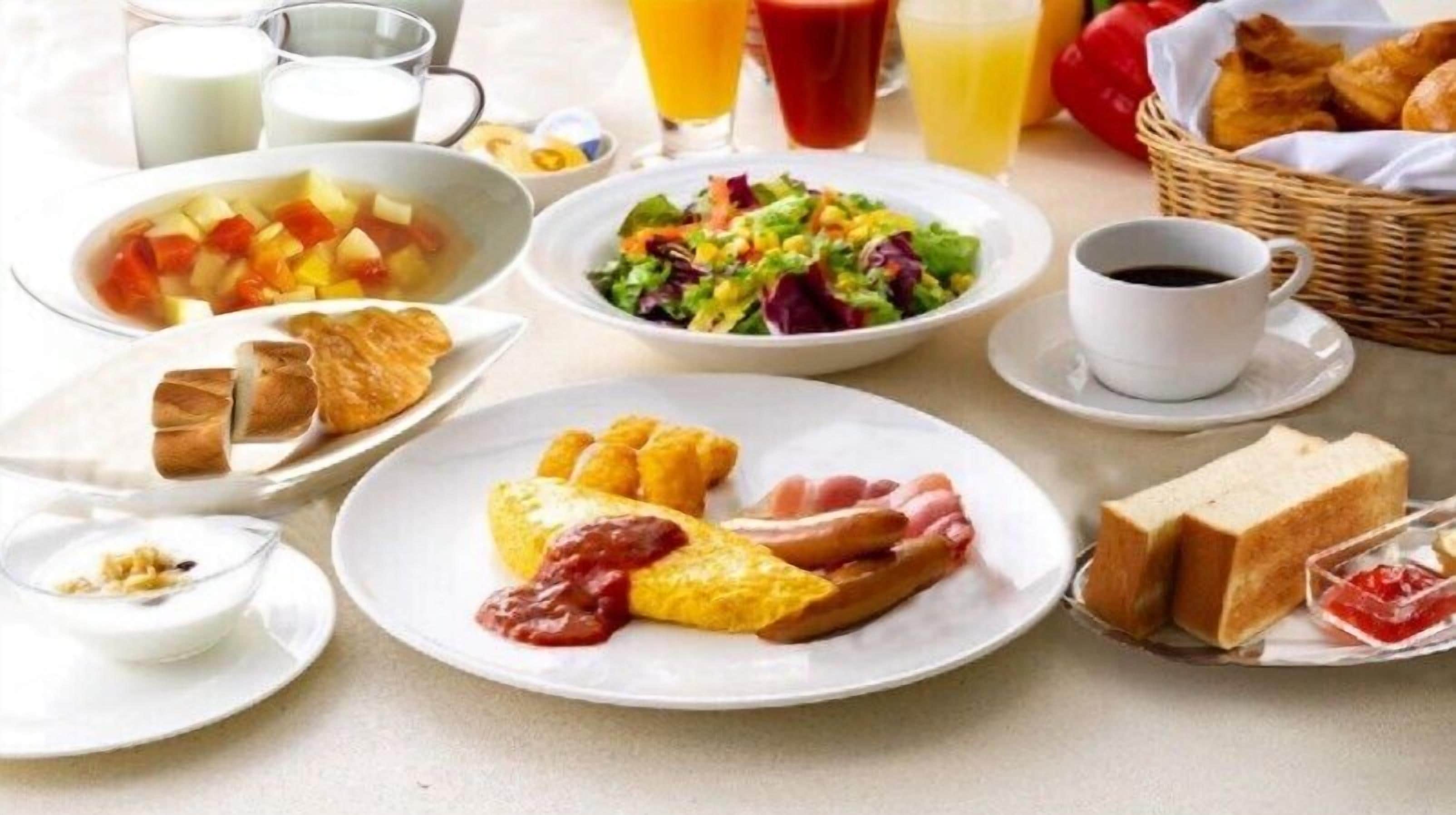 A breakfast table with various dishes including toast, eggs, sausages, and a salad.