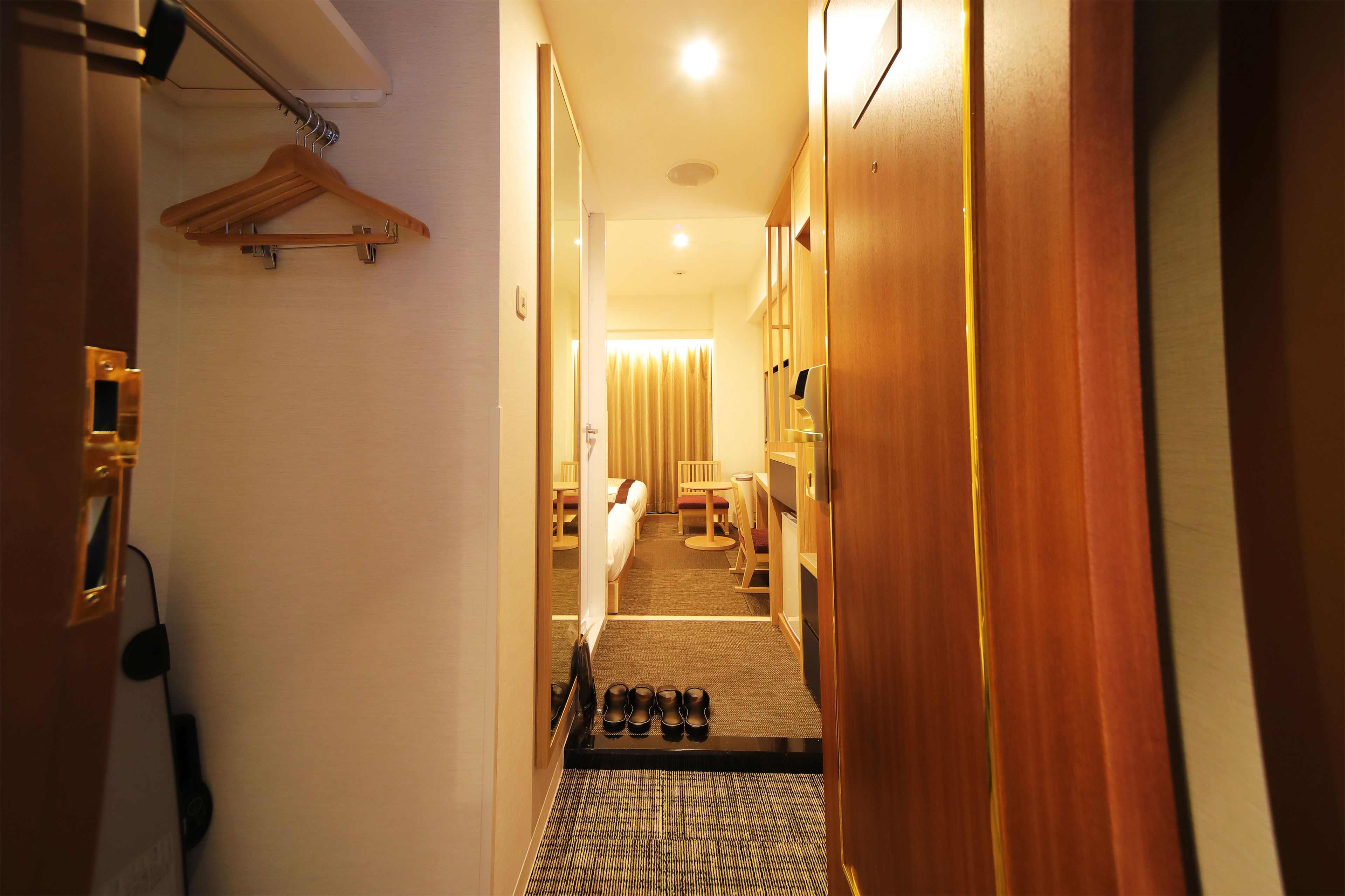 Ein Hotelgang mit einem Bett, einem Schreibtisch und einem Schuhregal.