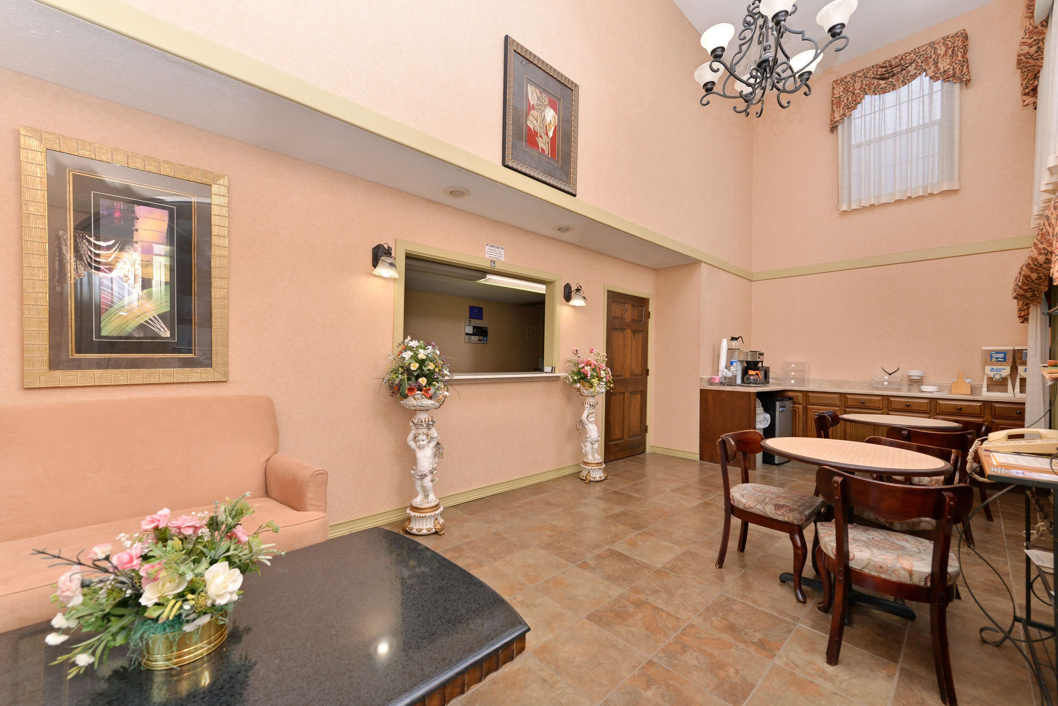 A reception area with a reception desk, a sofa, a dining table with chairs, and a chandelier.