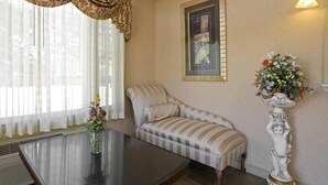 A room with a sofa, a table with a vase of flowers, a framed picture on the wall, and a tall white statue. - Americas Best Value Inn Anderson, SC (Anderson)