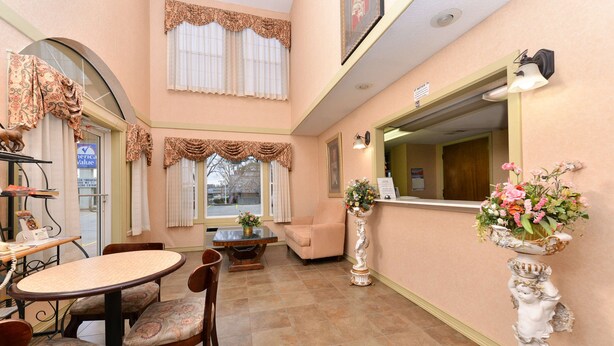 A hotel lobby with a reception desk, seating area, and a decorative vase with flowers. - Americas Best Value Inn Anderson, SC (Anderson)