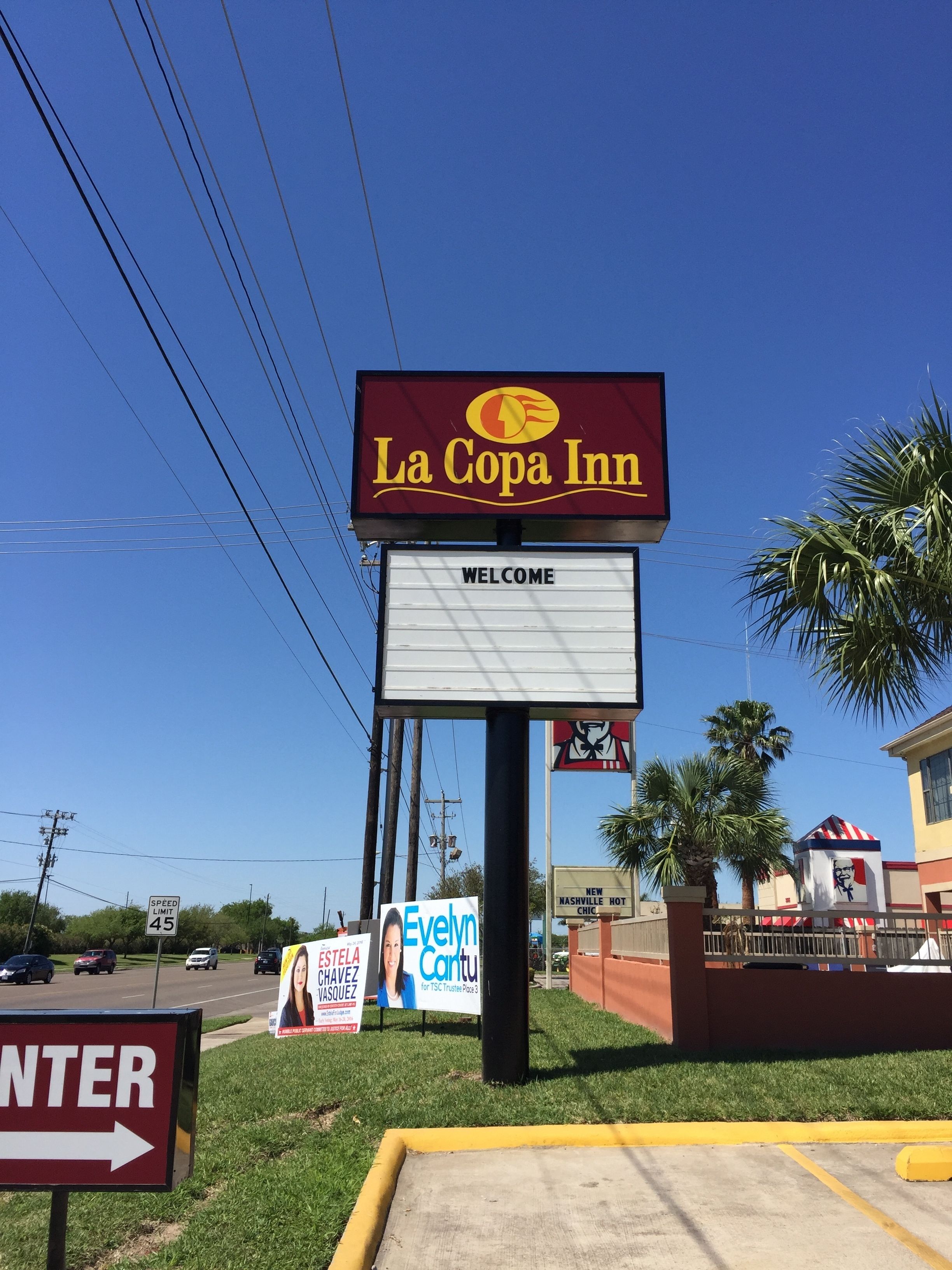 A La Copa Inn sign with a welcome message, a speed limit sign, and directional arrows.