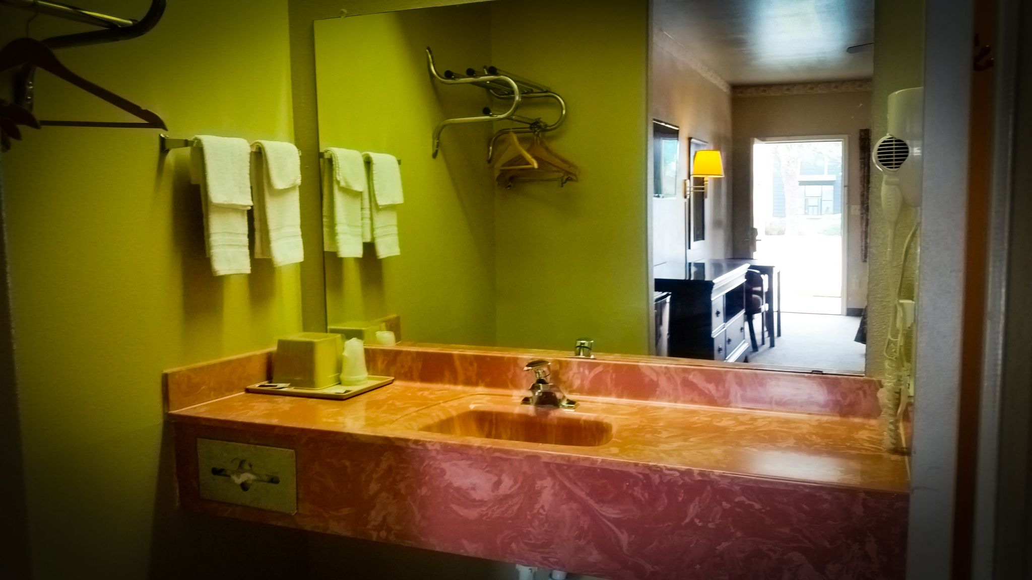 Un baño con lavamanos de mármol, espejo y toallero.