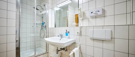 Un baño moderno con ducha de vidrio, un lavabo blanco y un espejo encima.