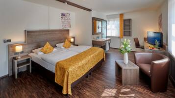 Ein Hotelzimmer mit einem großen Bett, einem Schreibtisch mit Stuhl, einem Fernseher und einem Badezimmer mit Spiegel und Waschbecken.