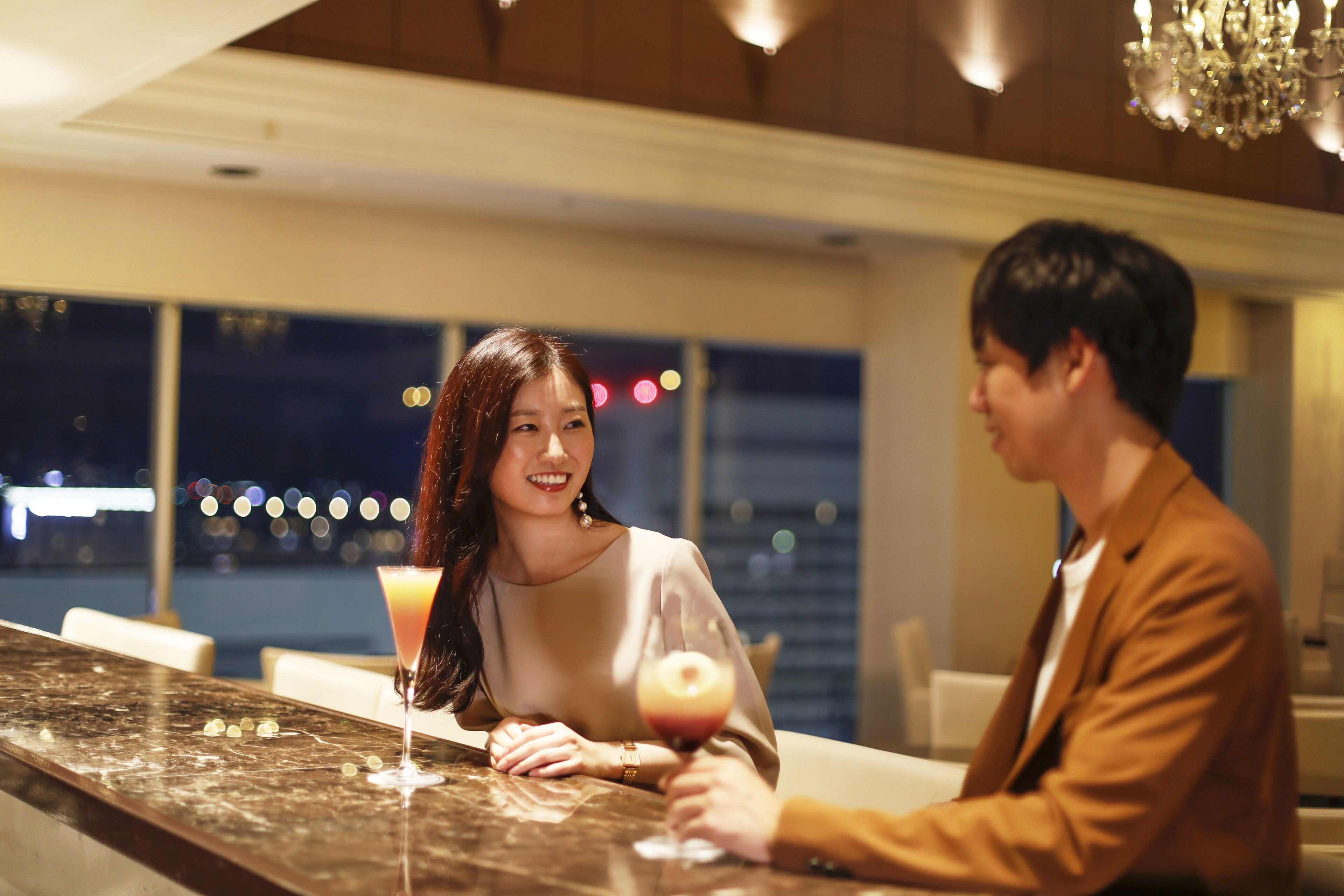 A couple seated at a bar with a city view in the background.