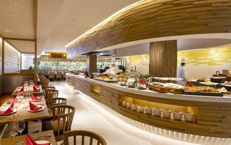 A modern restaurant with a curved counter, wooden accents, and a view of the outdoors.