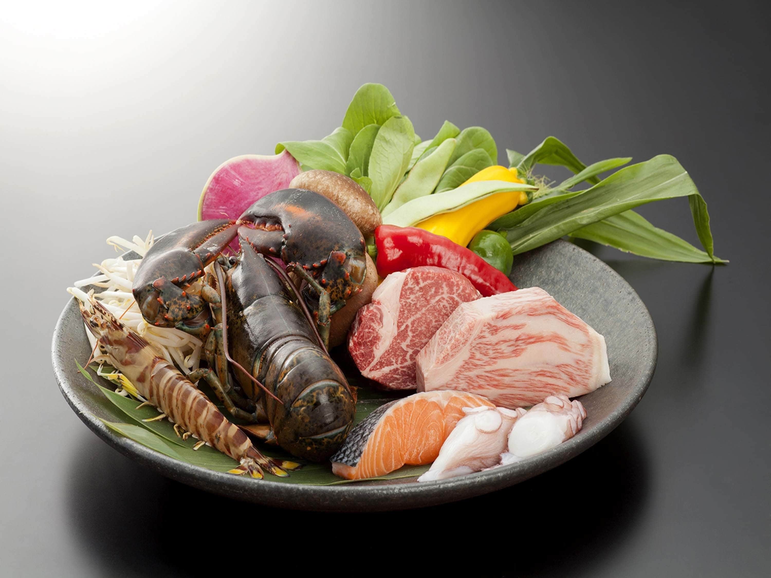 A plate of seafood including lobster, salmon, and other fish, with vegetables and greens.