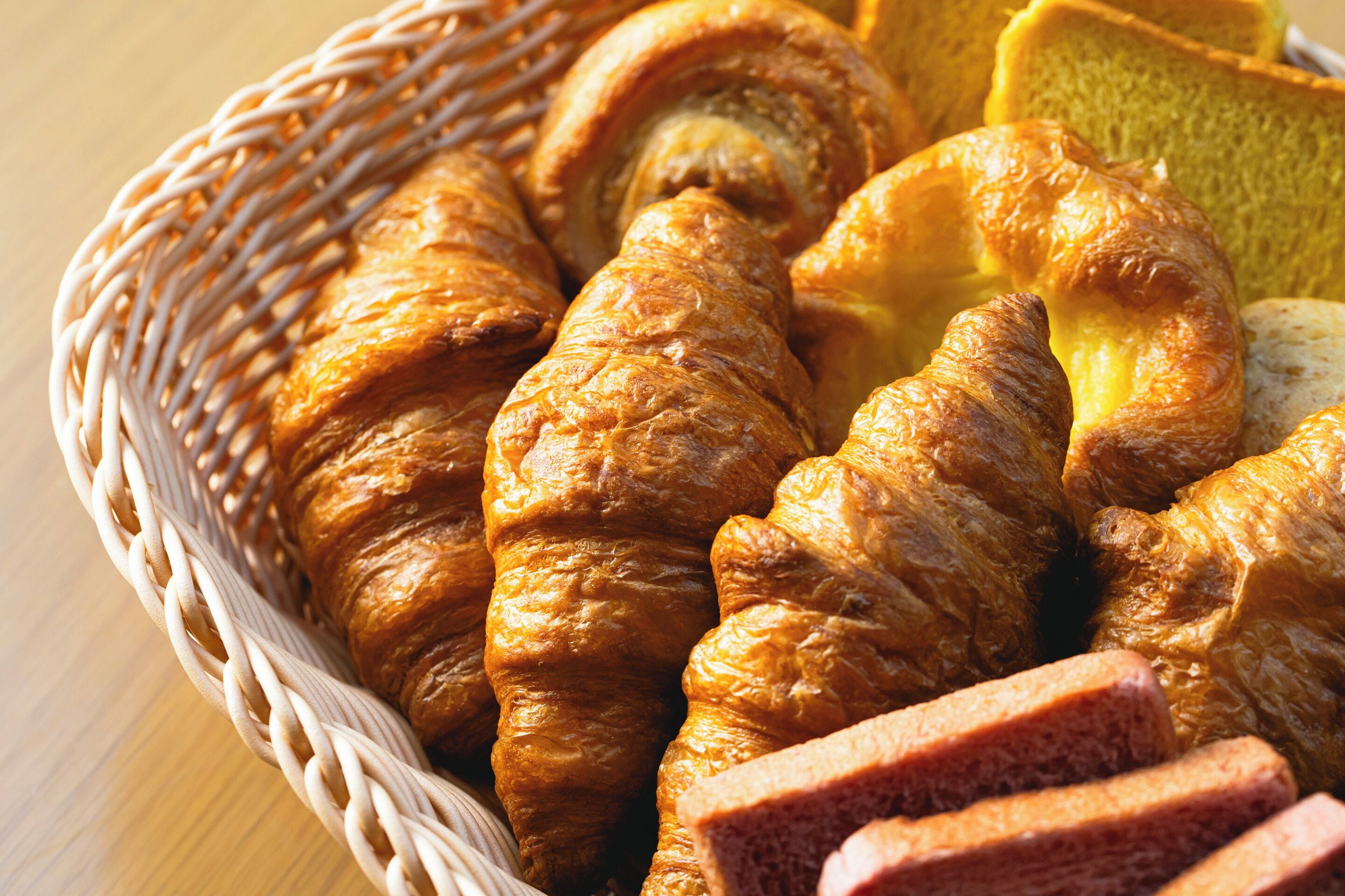 Een mand met croissants en sneetjes brood.