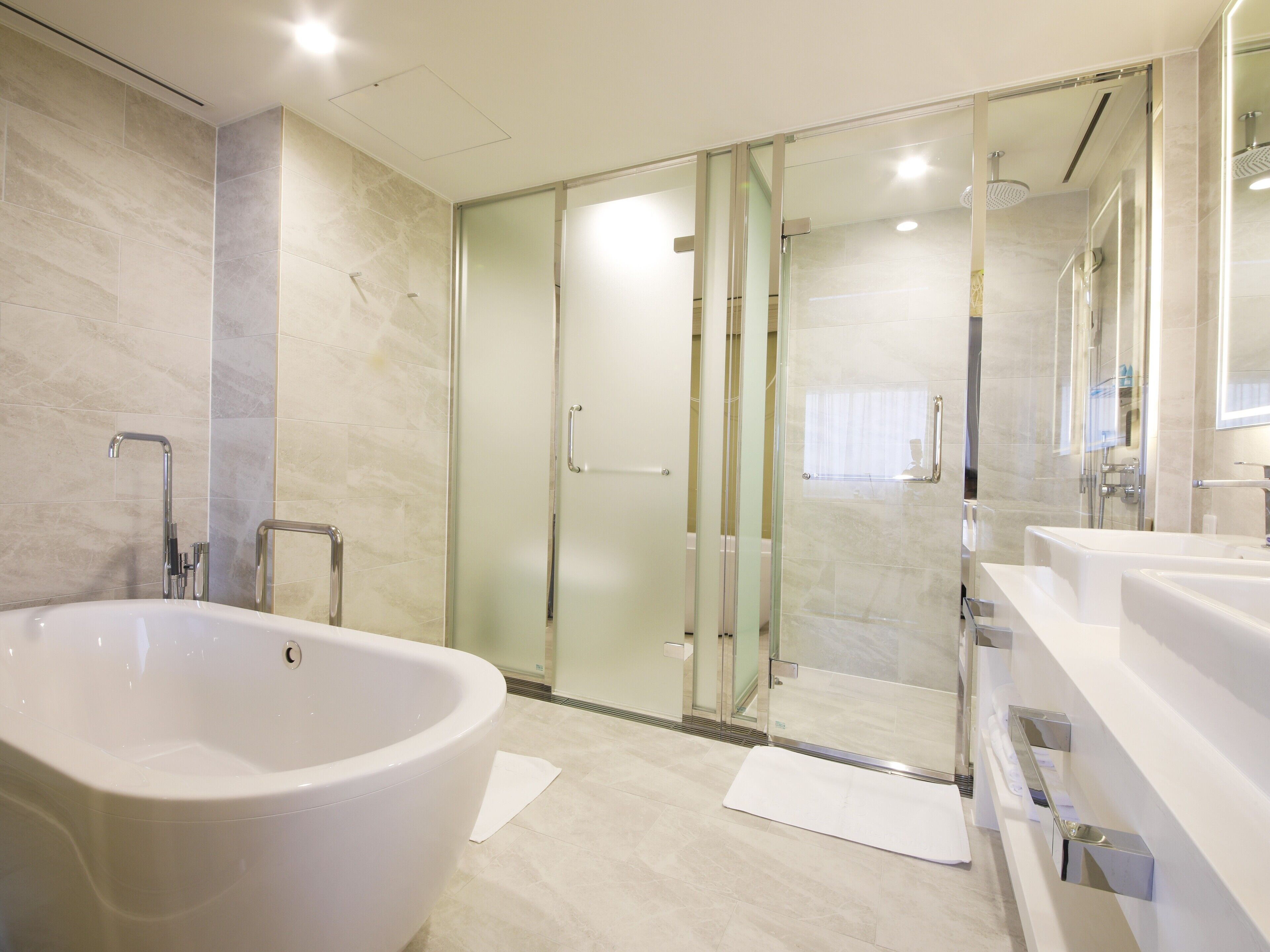 Un baño moderno con una bañera independiente, ducha con mampara de vidrio y tocador con espejo.