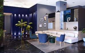Una sala de estar moderna con un sofá modular, sillas azules, una mesa de centro y un arreglo de plantas decorativas.