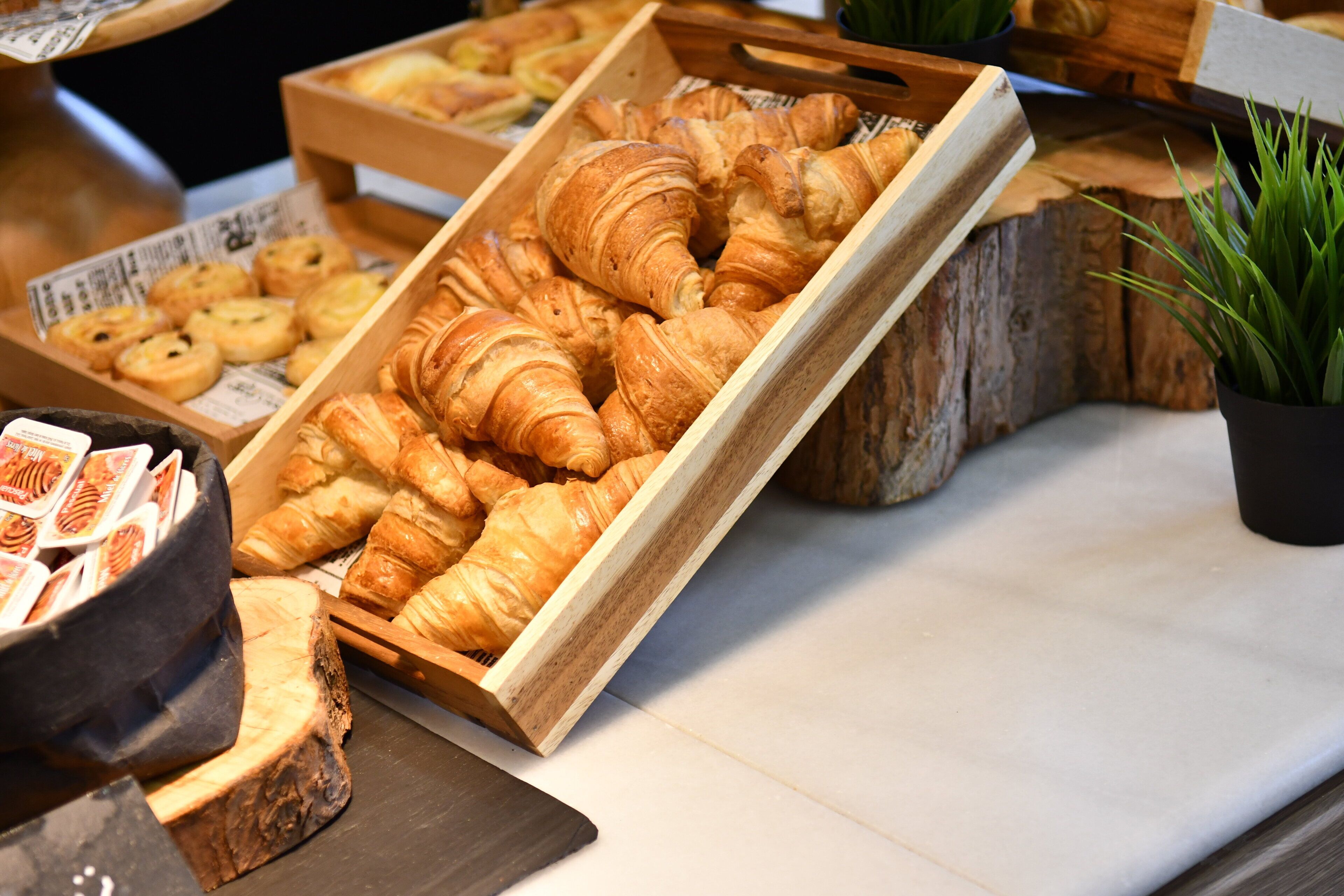 Diverse gebakjes gepresenteerd in houten doosjes op een aanrecht.