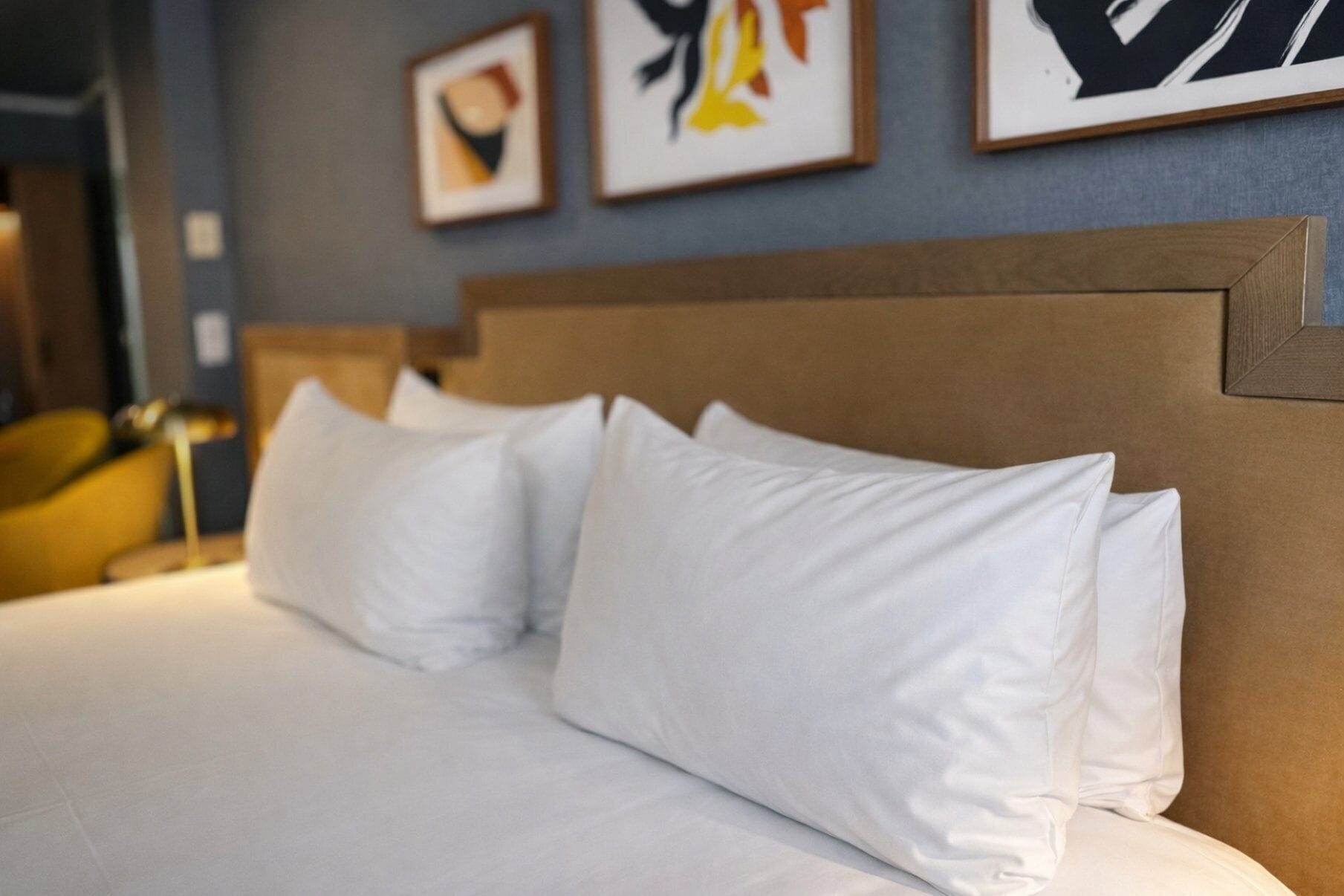 Una cama bien hecha con sábanas blancas y un cabecero de madera en una habitación de hotel.