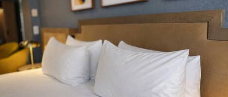 Una cama bien hecha con sábanas blancas y un cabecero de madera en una habitación de hotel.