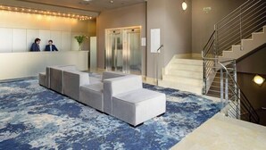 Un moderno vestíbulo con un mostrador de recepción, zona de estar y una escalera.
