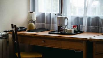 A wooden desk with a lamp, a coffee maker, and a tray with cups and a phone.