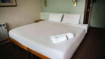 Ein Hotelzimmer mit einem großen Bett, zwei Nachttischlampen, einem gerahmten Bild an der Wand und einer Heizung.