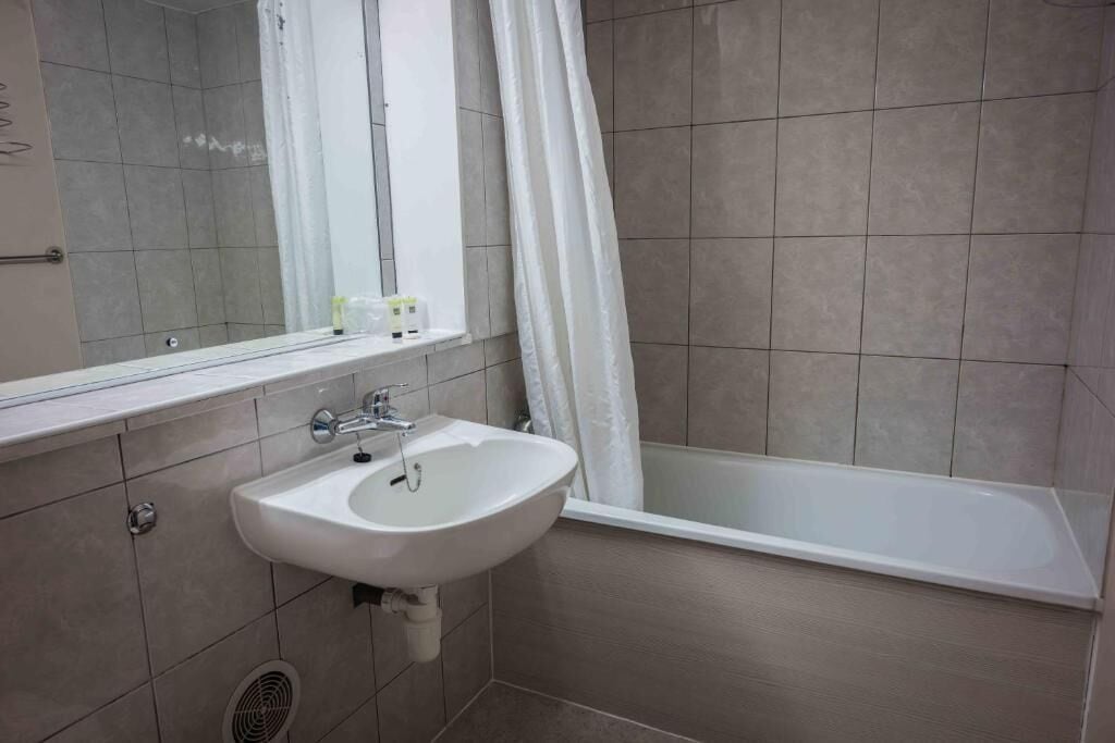 Een badkamer met een wastafel, spiegel en bad.