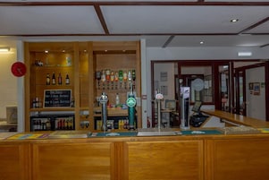 Uma área de bar com várias torneiras de cerveja, um caixa registradora e um anúncio de promoção para o bar.
