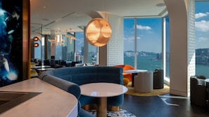 A modern hotel lobby with a large seating area, a round table, and a view of the city through large windows. - Mondrian Hong Kong (Kowloon)