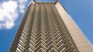 A tall, modern building with a zigzag pattern of windows and a prominent entrance with glass doors. - Mondrian Hong Kong (Kowloon)