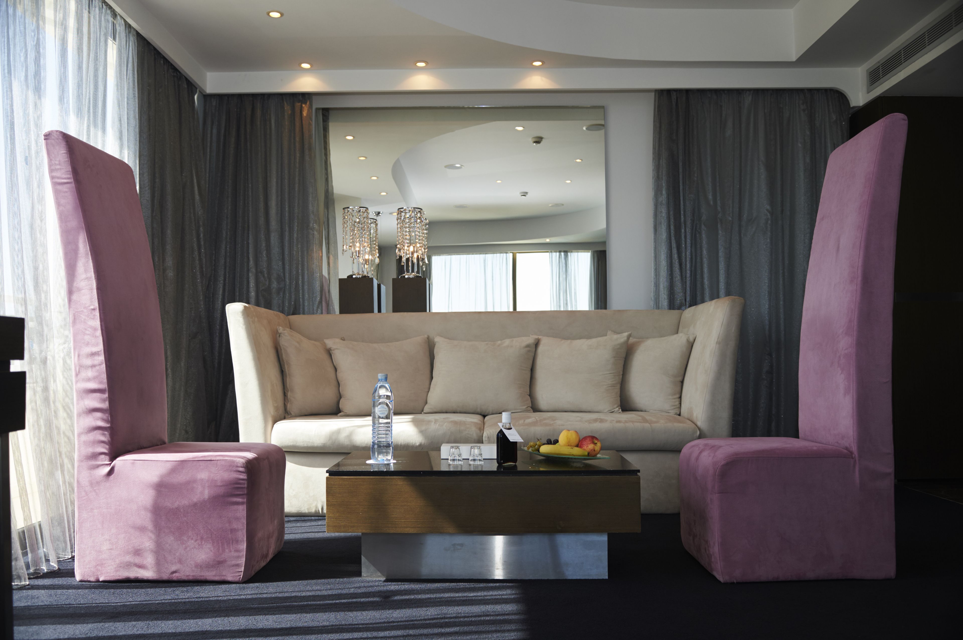 Ein modernes Wohnzimmer mit einer Couch, zwei Sesseln, einem Couchtisch und einer Deckenleuchte.