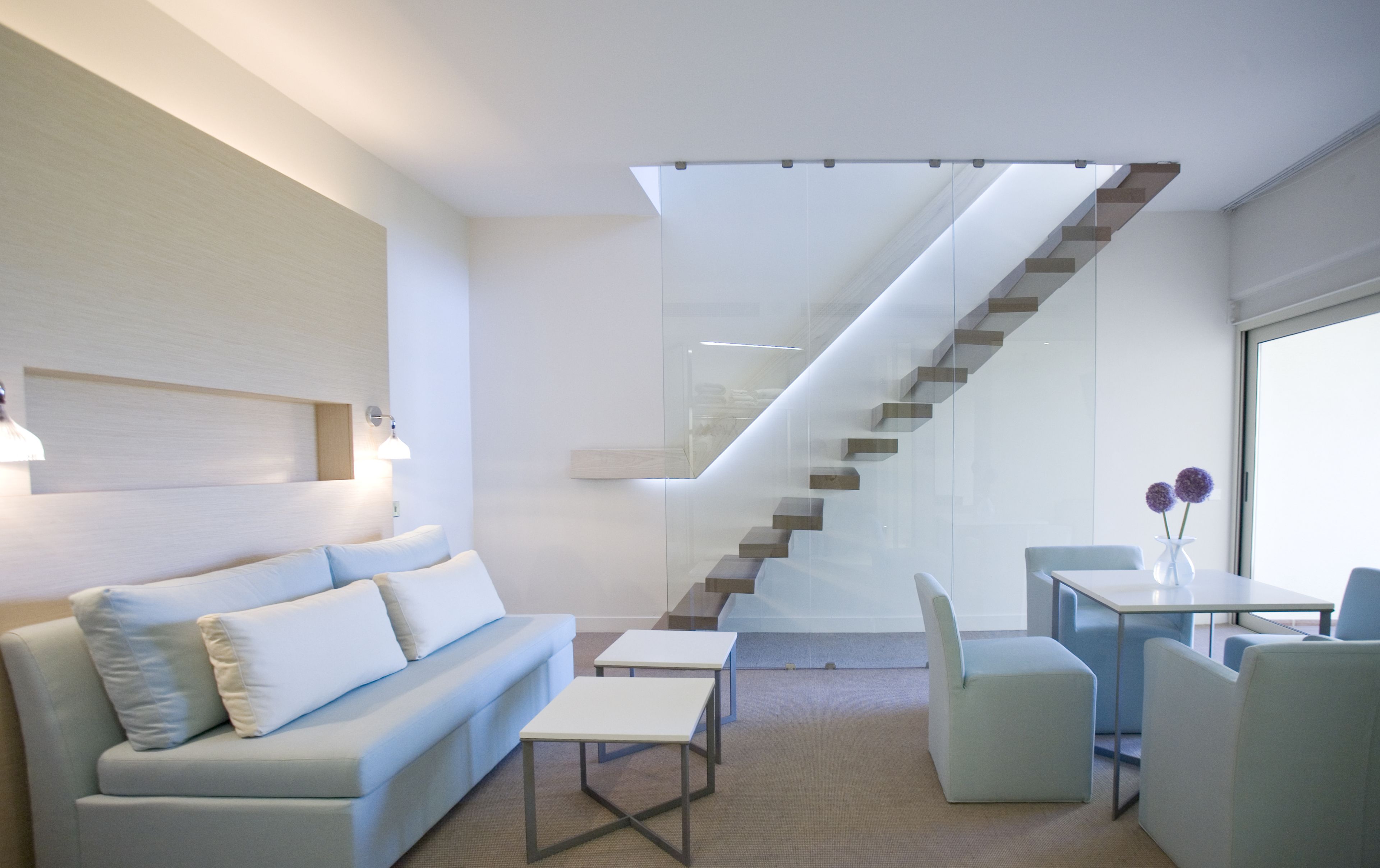 Un salon moderne avec un escalier, un canapé, une table basse et un coin repas.