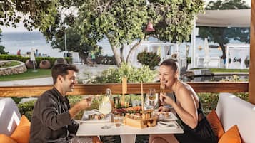 Enjoy a meal with a view of the sea from this outdoor dining area surrounded by lush greenery.