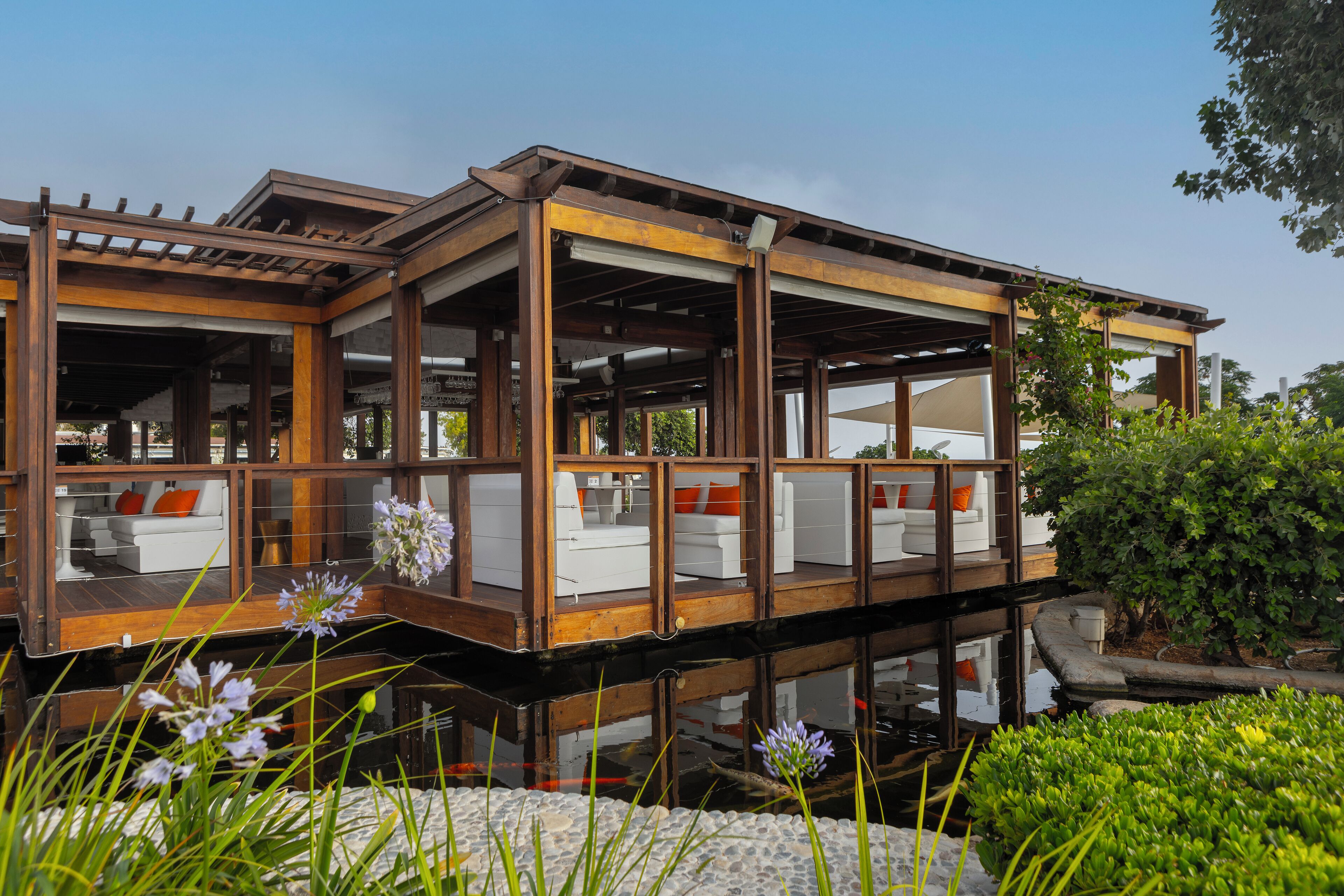 A modern houseboat with multiple levels, outdoor seating, and a garden area.
