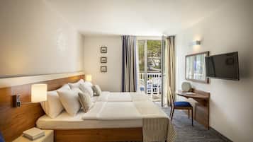 Habitación de hotel con una cama grande, un escritorio, un televisor y vistas al exterior.