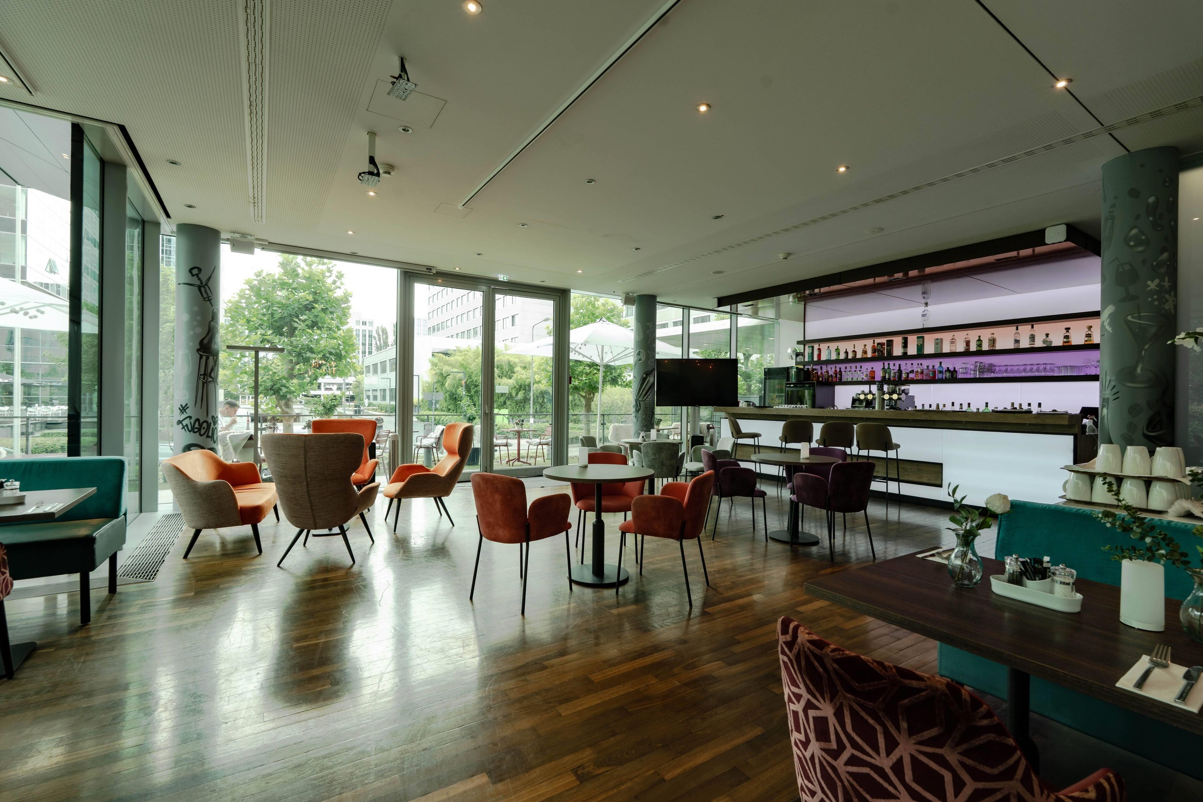 Ein modernes Interieur mit Barbereich, Sitzgelegenheiten und großen Fenstern.