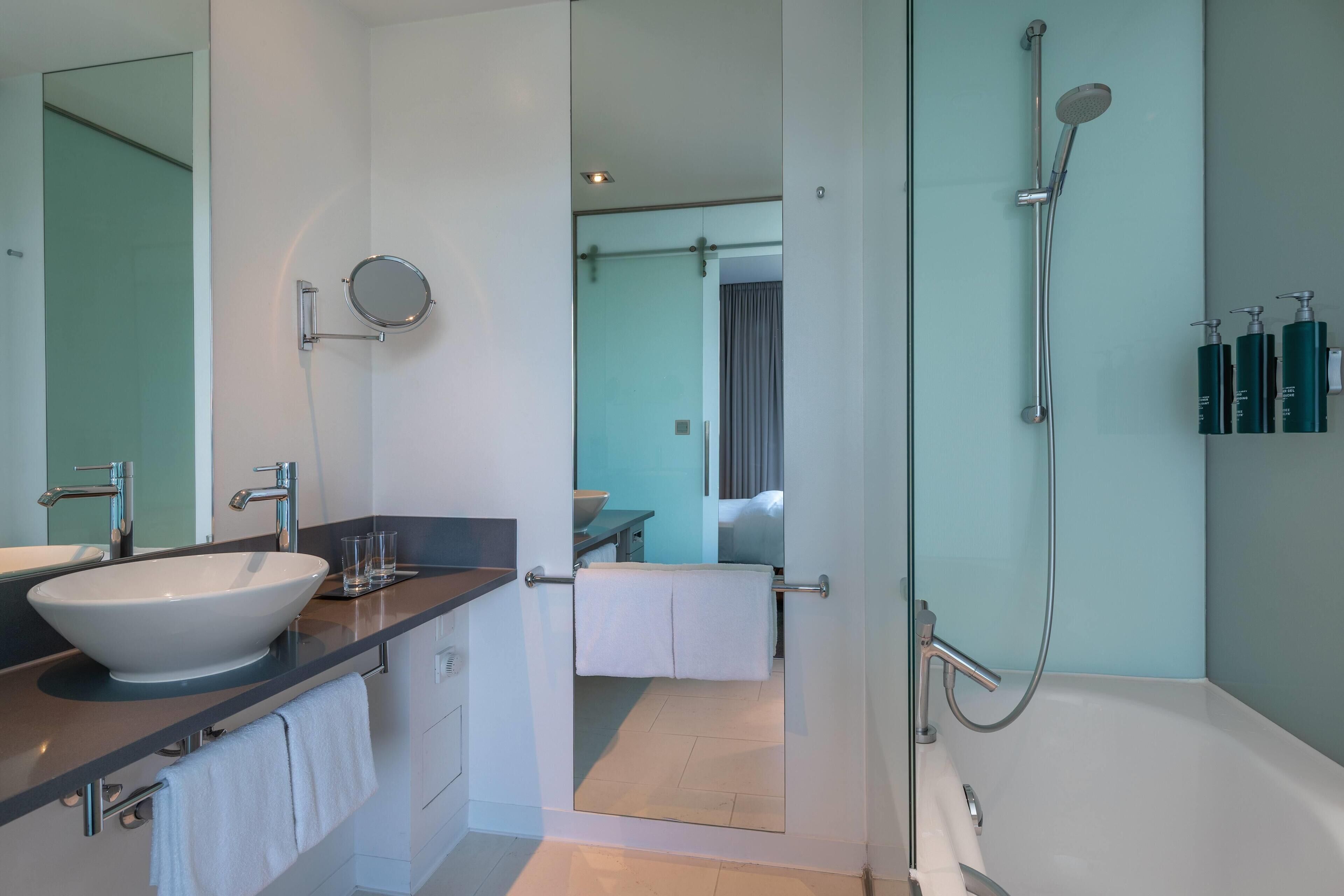 A modern bathroom with a large sink, mirror, and shower.