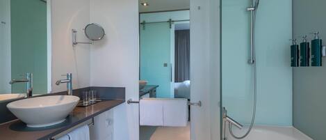 A modern bathroom with a large sink, mirror, and shower.