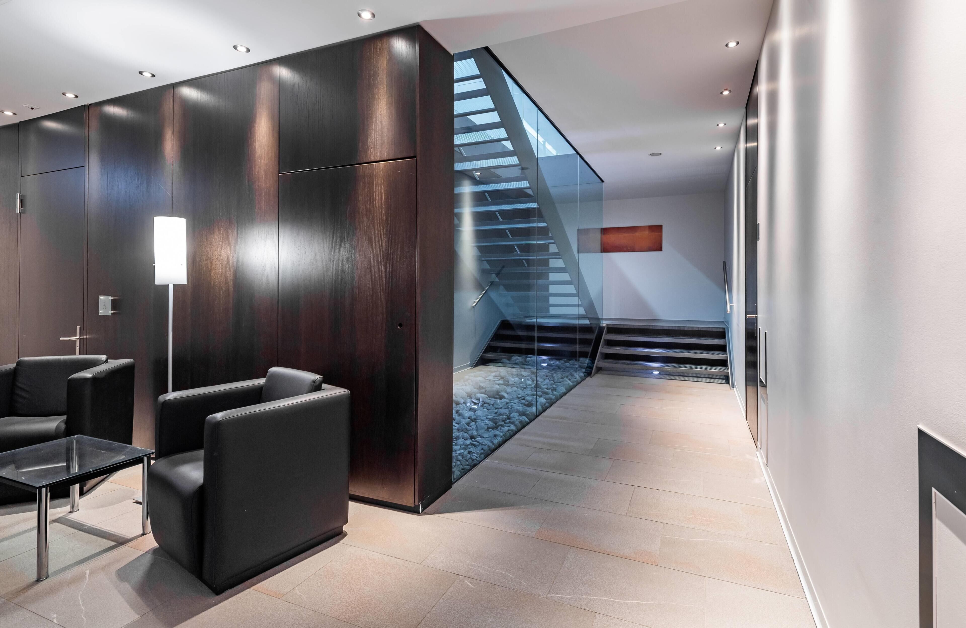 Eine moderne Lobby mit Treppe, Sitzgelegenheit und einer Glastrennwand.