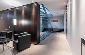Eine moderne Lobby mit Treppe, Sitzgelegenheit und einer Glastrennwand.