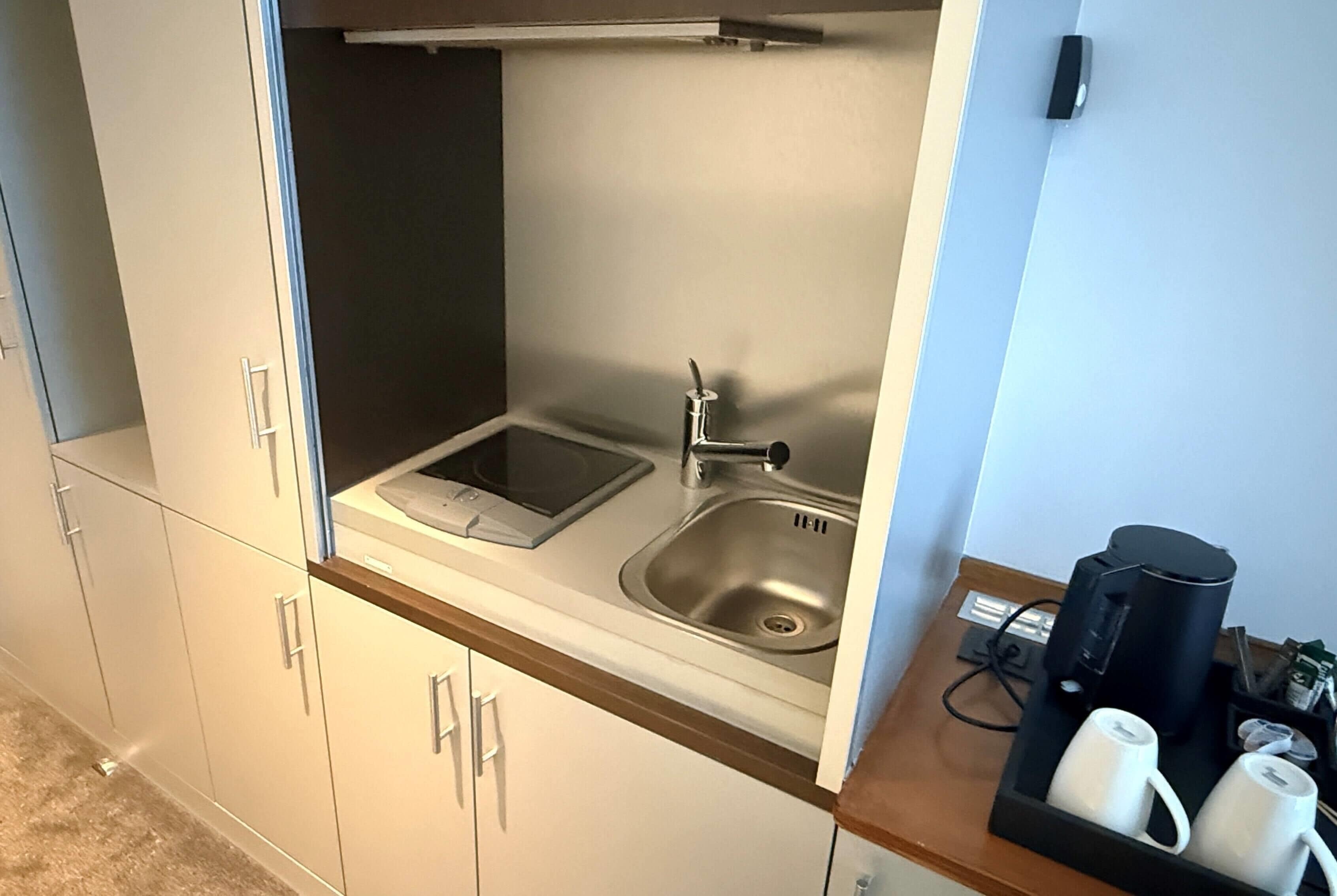 A compact kitchenette with a built-in sink, a stovetop, and a coffee maker.