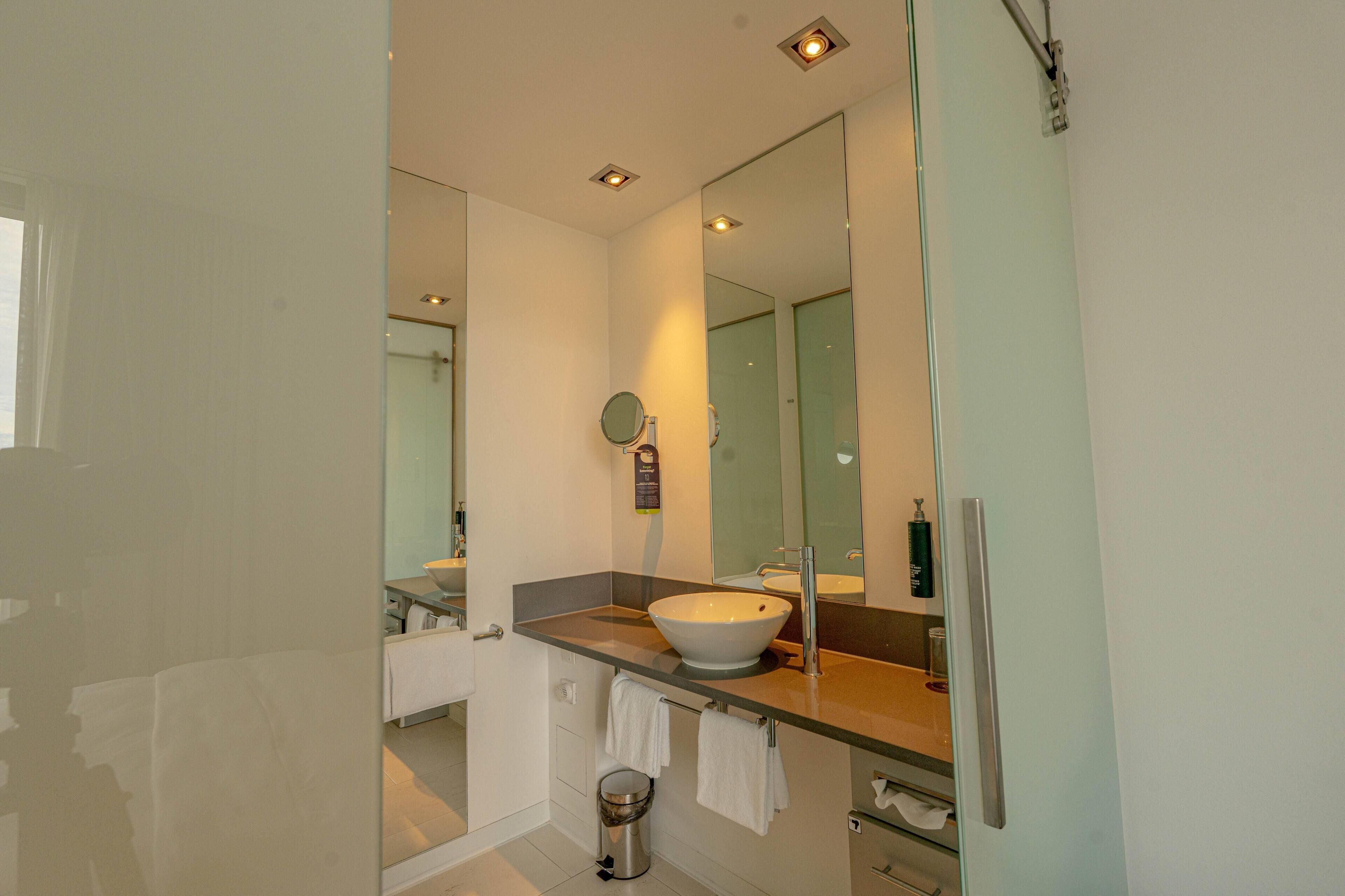 A modern bathroom with a large mirror, a vessel sink, and a glass shower enclosure.