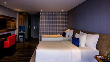 Una habitación de hotel moderna con sofá cama, televisión, minibar y pared con estampado.