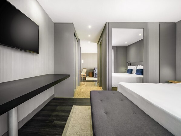 Una habitación de hotel moderna con televisión de pantalla plana, un sofá, una cama y una mesita.
