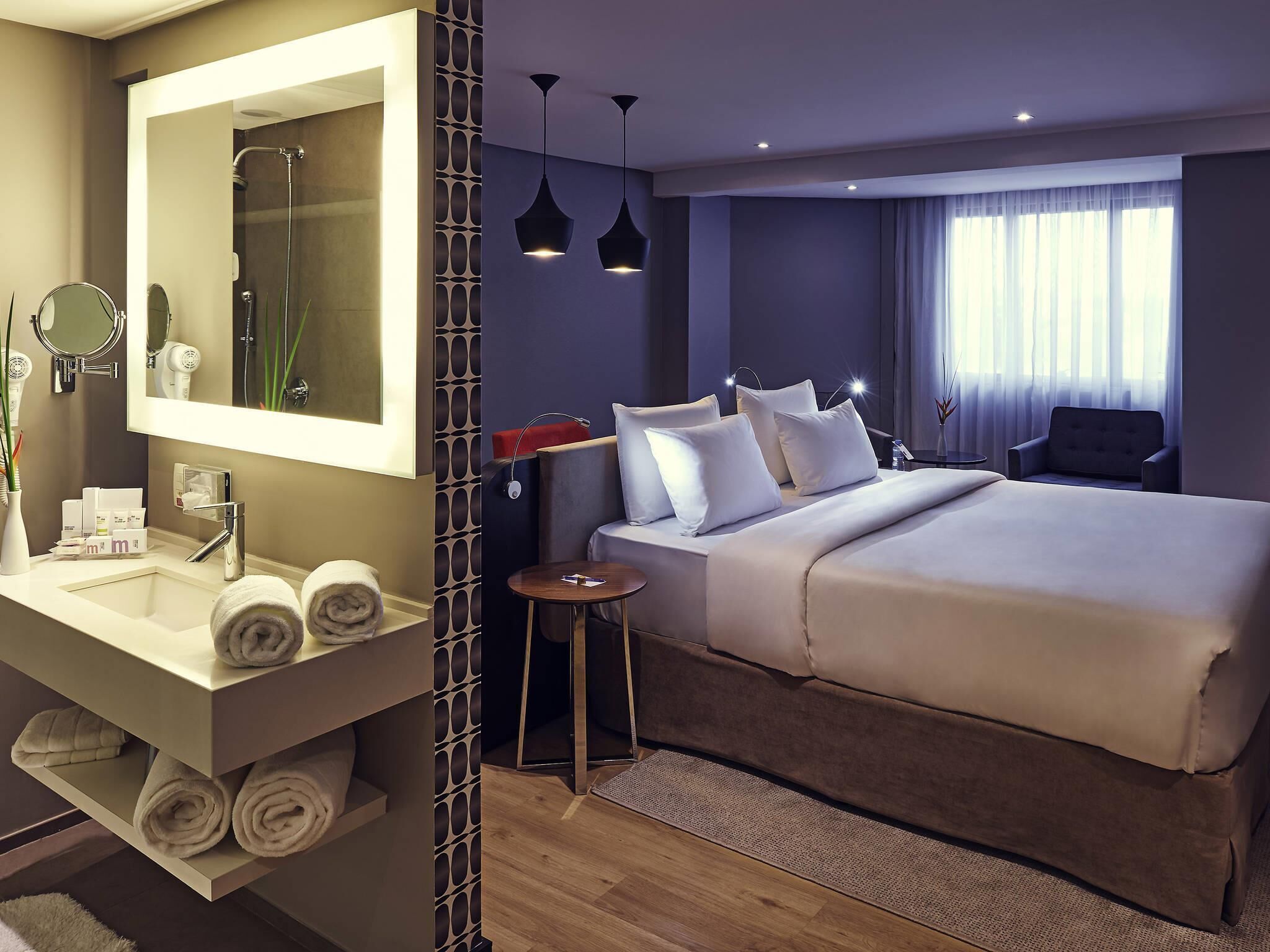 A hotel room with a large bed, a bathroom with a mirror, towels, and toiletries.