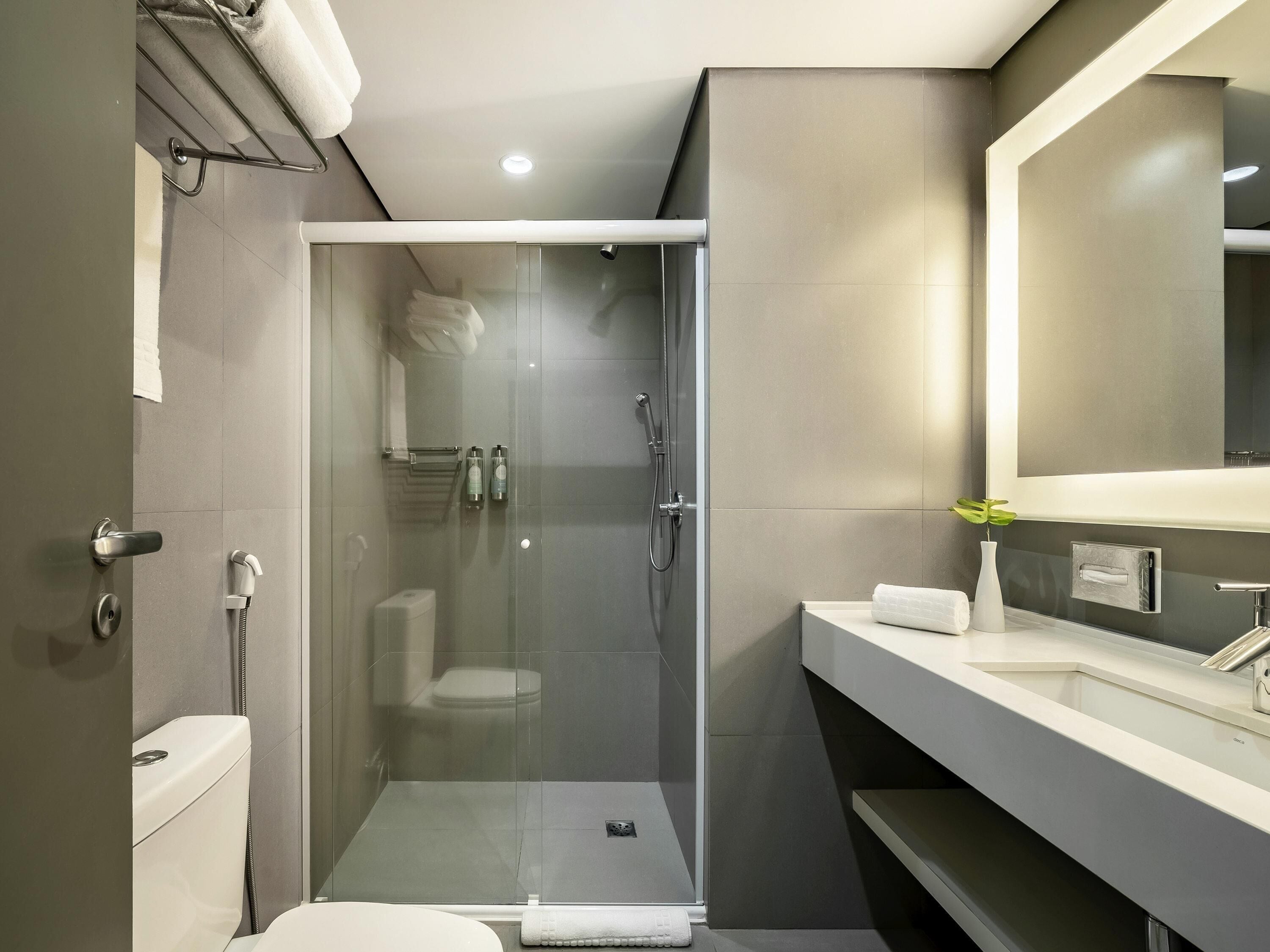 Une salle de bain moderne avec une douche à parois de verre, des toilettes et un meuble-lavabo avec un miroir.