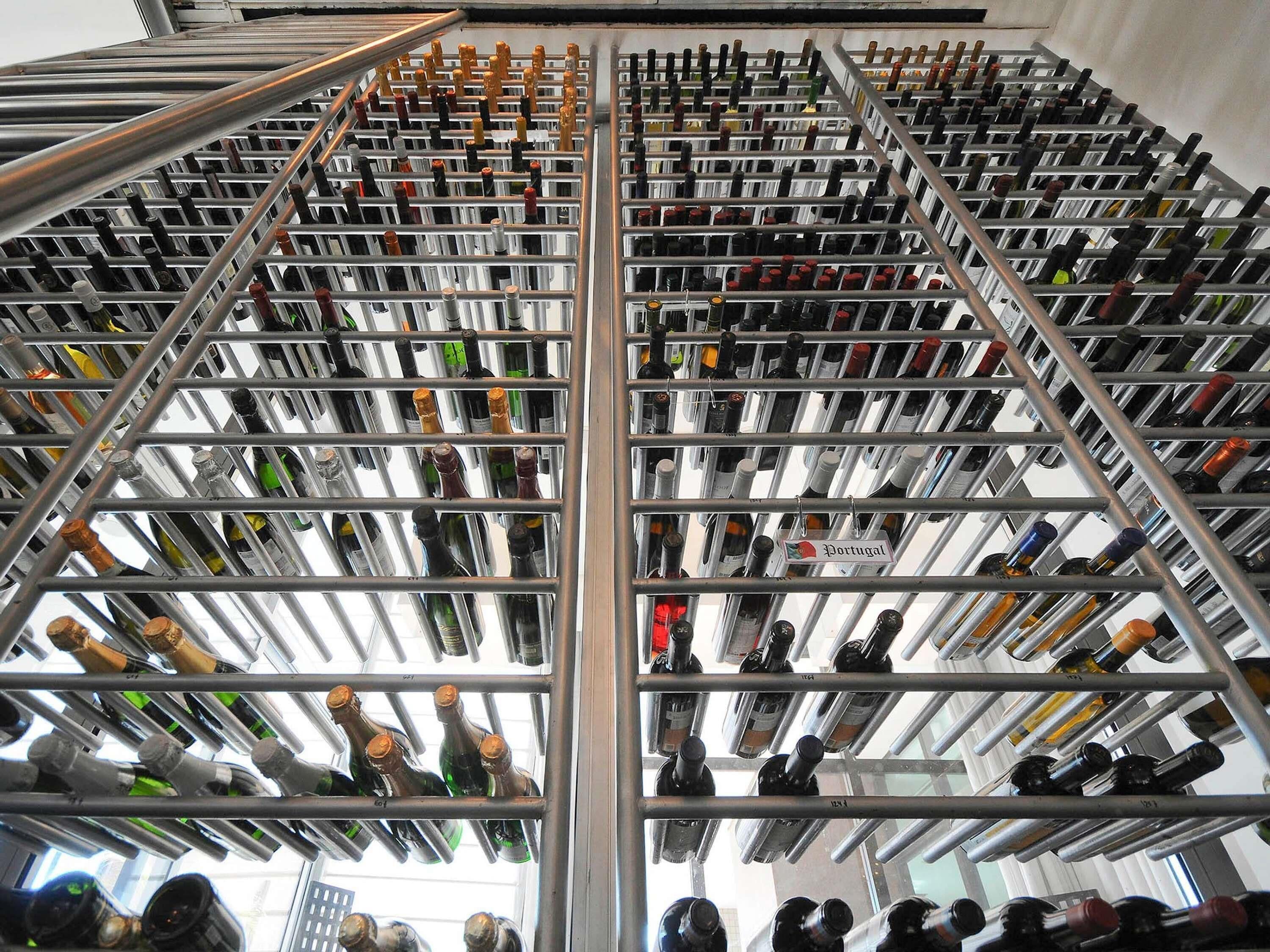 A large wine rack with multiple bottles, a sign indicating 'Portugal,' and a metal structure.