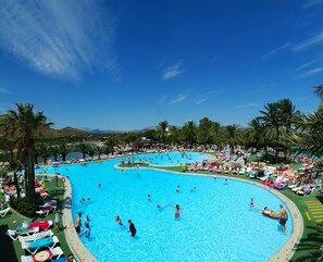 A large outdoor swimming pool surrounded by palm trees and lounge chairs.
