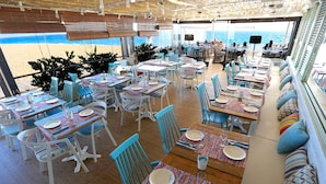 A beachside restaurant with tables and chairs arranged for dining, overlooking the sea. - KAKTUS Hotel Volga (Calella)