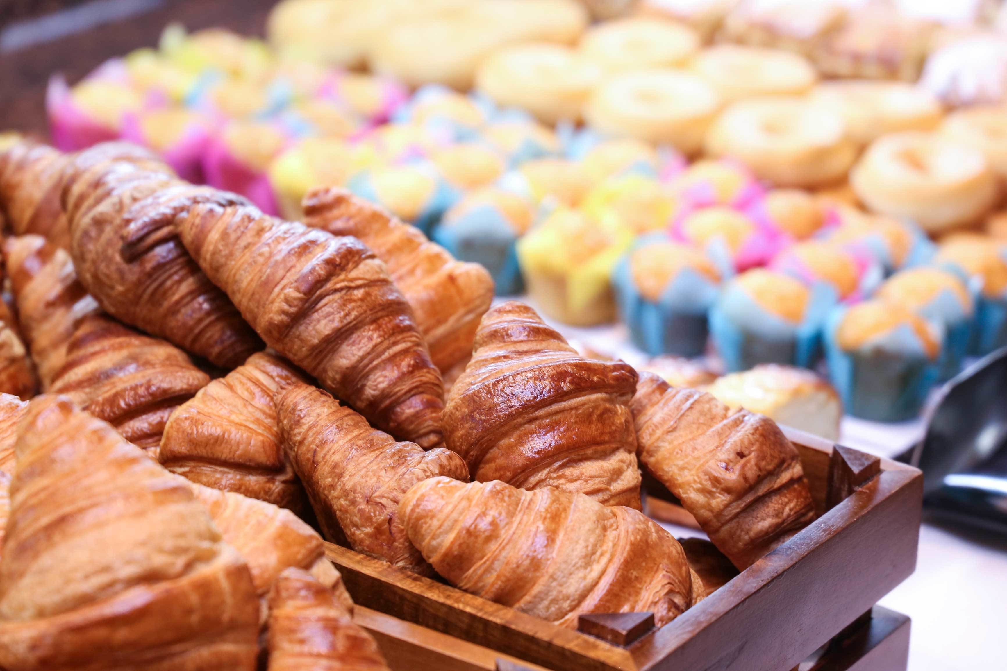A display of pastries including croissants and colorful cupcakes.
