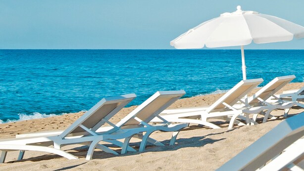A beach with white lounge chairs and a white umbrella. - KAKTUS Hotel Volga (Calella)